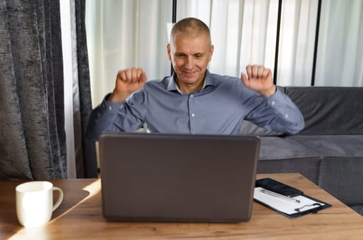 A businessman working at a computer rejoices at a successful deal.