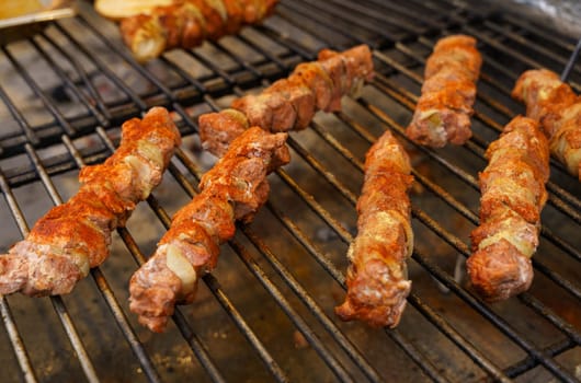 Fried meat with onions on a skewer lies on the grate. Polish street food