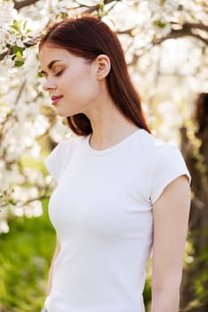 portrait of a lovely, beautiful woman against the backdrop of a flowering tree in a white T-shirt. High quality photo
