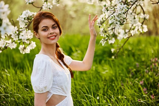 Portrait of a beautiful woman looking at the camera touching the flowers of an apple tree