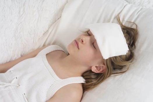 A sick teenage girl lies on her head with a wet rag to remove heat.