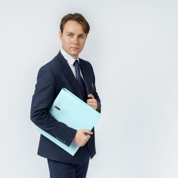 A businessman in a blue suit holds folders on a white background.