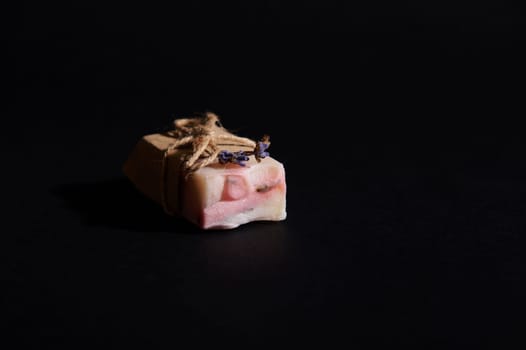 Details on a bar of handmade organic soap of pink marble color with natural ingredients, isolated on black background