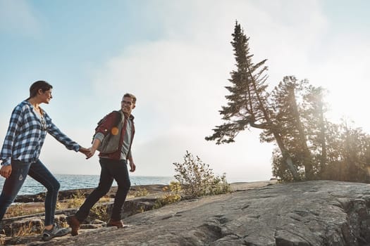 Boring dates is not for us. a happy couple out hiking hand in hand.