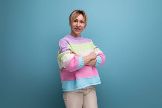 smiling blond woman in casual outfit on blue background with copy space