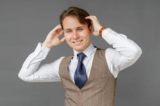 An emotional portrait of a businessman who touches his head with his hands. Gray background