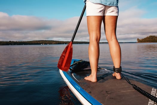 Go where the water takes you. an unrecognizable woman paddle boarding on a lake.