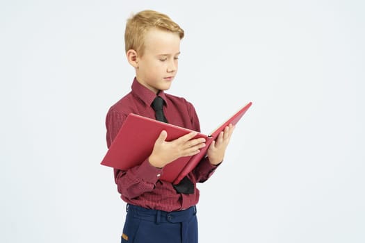 Pupil holds an open book in his hands and reads, isolated background.