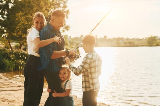 Conception of vacation. Father and mother with son and daughter on fishing together outdoors at summertime.