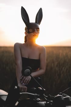 Sexy motorcyclist woman on motorcycle. Attractive driver in rabbit mask on face