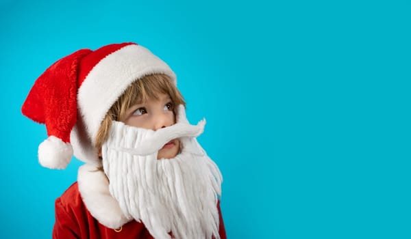 Portrait of adorable boy in Santa Claus hat and beard on blue. Christmas banner