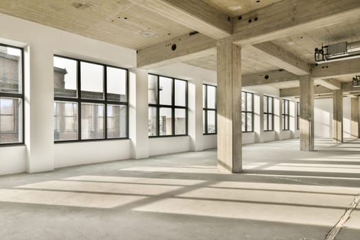 an empty room with large windows and a concrete floor