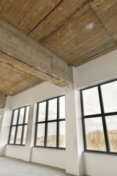 a room with large windows and a wooden ceiling