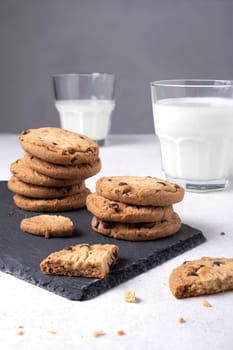 Oatmeal chocolate chip cookies on a slate serving board and milk