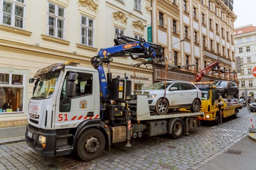 11 November 2022 Prague, Czech Republic. Two tow trucks load two cars onto a trailer from the parking lot.
