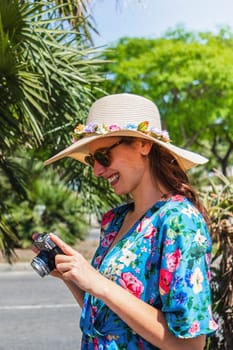 Vertical portrait of young happy woman on holidays looking at pictures in camera.
