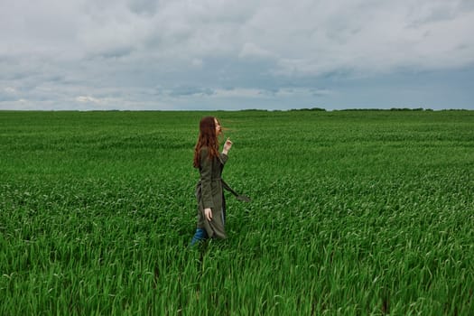a woman in a dark coat walks through a field with tall grass in windy, rainy weather. High quality photo