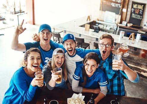 Sports fans More like sports fam. a group of friends cheering while watching a sports game at a bar.