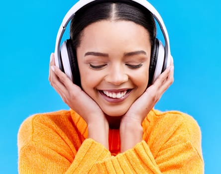 Headphones, happy music and woman in studio, blue background and backdrop. Smile, female model and listening to radio, streaming album and excited audio connection, sound and subscription to podcast