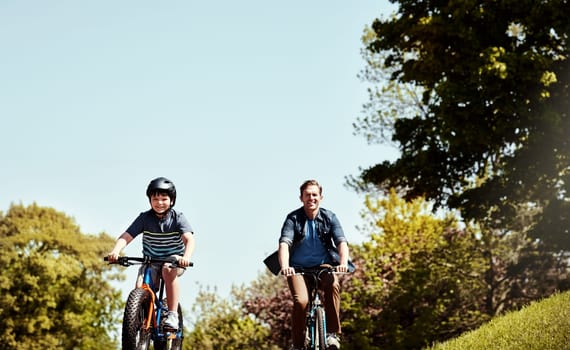 Lifes just better outdoors. a young boy and his father riding together on their bicycles.