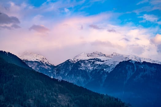 monsoon clouds moving over snow covered himalaya mountains with the blue orange sunset sunrise light over kullu manali valley