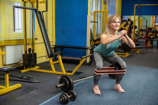 Young woman works out at the gym doing squats