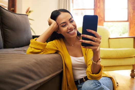 Smile, relax and a woman with a phone for an app, communication and social media. Happy, funny and a girl reading a text message, chat or notification on a mobile in the living room of a house.