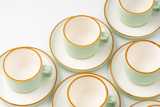 A set of white and pastel green ceramic teacups with orange outlines