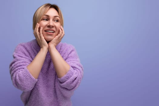 portrait of dreamy charming cute blondie woman in lavender sweater on purple background with copy space