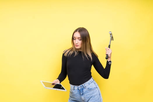 Woman with tablet and hammer, Studio lighting yellow background isolated, copy space