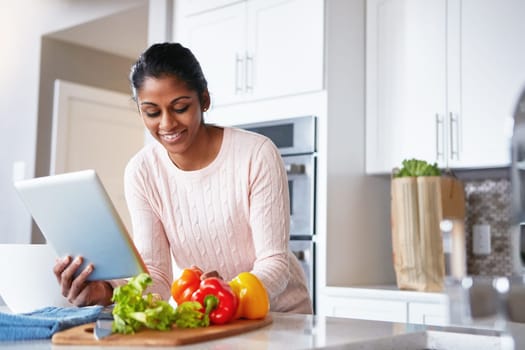 So many cooking apps with just one tap. a young woman using a digital tablet while preparing a healthy meal at home.