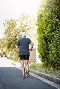 Off to conquer his fitness goals. Rear view shot of a senior man out for a run