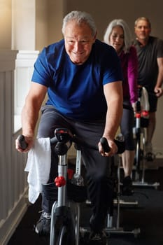 Your health is an investment not an expense. a group of seniors having a spinning class at the gym.