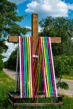 The Christian cross is decorated with ribbons of rainbow colors.
