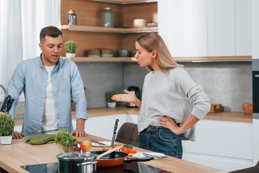 Arguing with each other. Couple preparing food at home on the modern kitchen