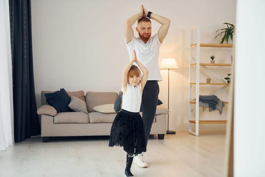 Teaching how to dance. Father with his little daughter is at home together