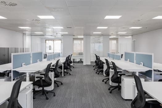 Spacious empty office in gray colors with comfortable office furniture without equipment with private areas for comfortable work of employees. Concept of a modern corporate space in a coworking center