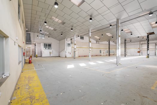 Parking garage with lights, light-colored walls, metal beams and ceiling prepared for renovation into a party hall. The concept of spacious premises before renovation