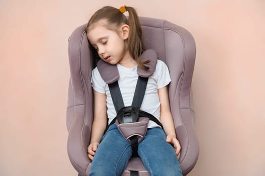 Preschool girl fastened sleeping in a car seat