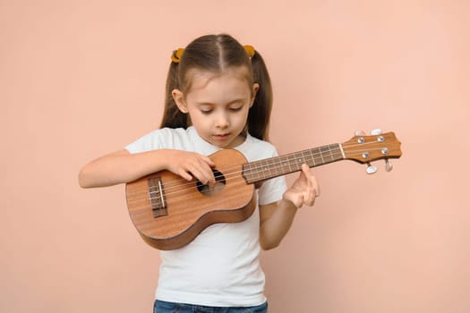 Preschool girl learning music by playing ukulele