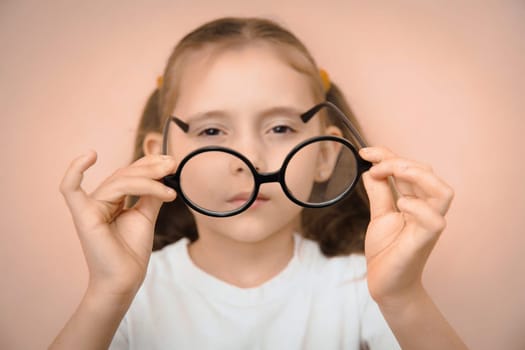 A little kid girl of elementary school age to choose the right glasses with a diopter