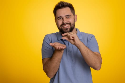 Young man showing a little bit gesture with sceptic smile showing minimum sign measuring small size