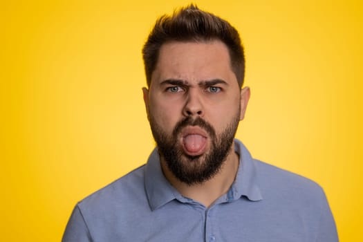 Cheerful funny bully caucasian man showing tongue making silly faces, fooling around, joking teasing