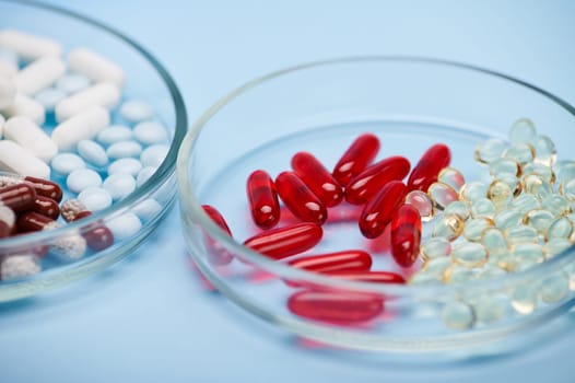 Still life with assortment of pharmaceutical pills in petri dish isolated on blue background. Pharmacy. World Health Day