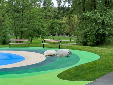 Recreational area in a park with two benches on colored ground