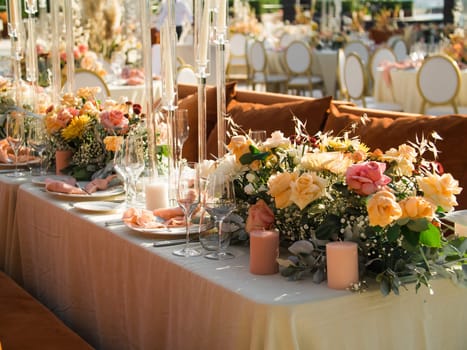 Wedding banquet concept. Chairs and round table for guests, served with cutler and, flowers and crockery and covered with a tablecloth