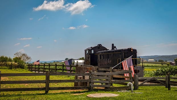 Restored Diesel Locomotive Approaches a Fence With Gently Waving American Flags
