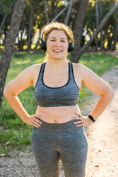 Fat body positivity woman and sports. Girl doing exercise for weight loss in the fresh air and laughing in camera after training
