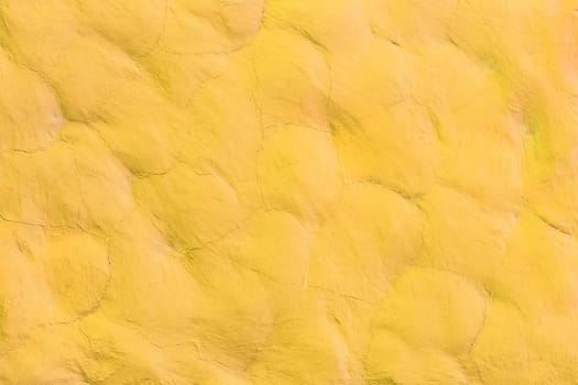 Yellow bright light vibrant paint on the stone surface wall texture abstract background pattern design