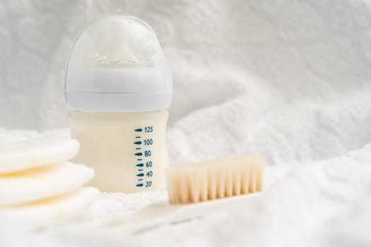 Bottle with milk formula and diapers with a brush, the concept of a pleasant meal after bathing